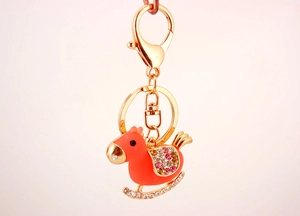 Detail of coral pink rocking horse keychain with crystal accents and golden lobster clasp