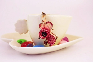 Close-up of a pink crystal mouse charm keychain with sparkling rhinestones on a white cup