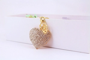 Détail macro du porte-clés en cœur avec cristaux et petit pendentif fleur doré