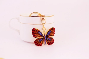 Close-up of rhinestone butterfly keychain hanging on a white ceramic cup with a golden rim
