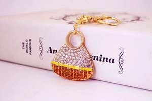 Detail of a crystal-encrusted gold handbag keychain with yellow enamel accents