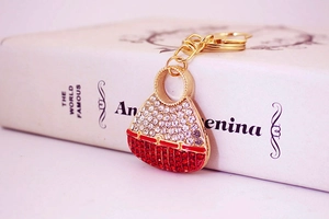 Detail showing red and white crystals on golden metal handbag keychain accessory