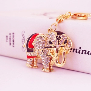 Elegant gold elephant keychain accessory featuring white rhinestones and enamel saddle