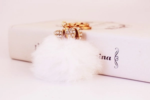 Dettaglio del portachiavi a pompon bianco con corona dorata decorata con strass lucidi