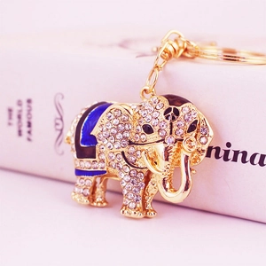 Golden elephant keychain featuring blue rhinestones and peace sign on white background