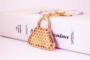 Detail of a golden handbag keychain with hollow flower pattern and polished finish