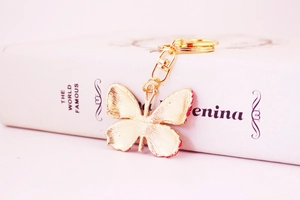 Detailed back view of a golden butterfly keychain showing brushed metal texture and ring
