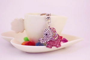 Detail of pink crystal elephant keychain with rhinestones hanging on a white ceramic cup