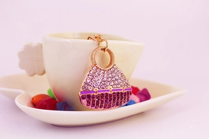 Close-up of a sparkling crystal handbag keychain hanging on a white ceramic cup edge