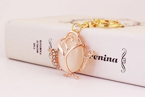 Close-up of rose flower keychain with cat eye stone and sparkling crystals on book