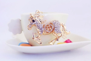 Gros plan d'un porte-clés cheval doré avec strass scintillants sur une tasse à café