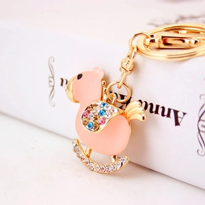 Pink rocking horse keychain with crystal rhinestones and gold plating on books