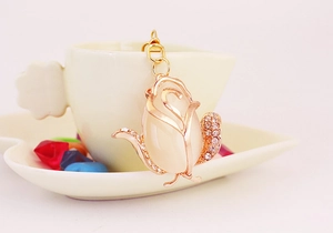 Close-up of rose gold keychain with opal stone flower and crystal leaves on white cup