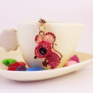 Cute mouse keychain pendant featuring rose pink crystals and gold metal on a white cup
