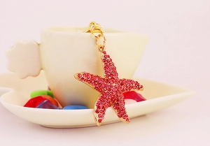 Gros plan du porte-clés étoile de mer en cristal rose sur le bord d'une tasse blanche