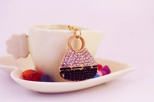 Close-up of luxury crystal handbag keychain hanging on a white coffee cup