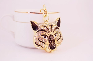 Detailed close-up of a rhinestone tiger head keychain hanging on a white porcelain cup
