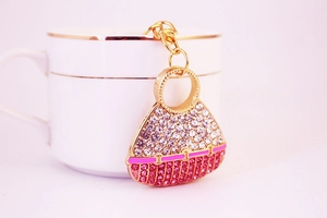 Detail of crystal encrusted handbag keychain with pink rhinestones on a ceramic cup
