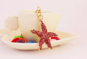 Détail d'un porte-clés étoile de mer en cristaux roses suspendu à une tasse