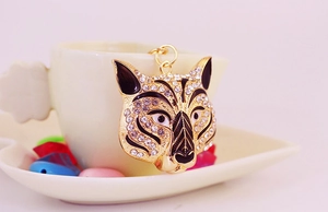 Detailed view of rhinestone leopard head keychain hanging on a white ceramic cup