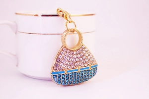 Detail of crystal encrusted handbag keychain hanging on a gold-rimmed white coffee cup