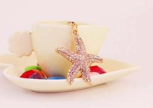 Gros plan détaillé d'un pendentif étoile de mer dorée avec cristaux mauves sur tasse