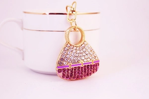 Detailed close-up of a sparkling crystal purse keychain with pink rhinestones on a gold base