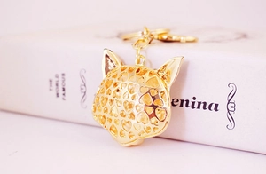 Detailed close-up of golden hollowed cat head keychain with intricate heart pattern
