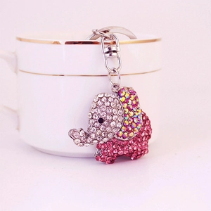 Pink crystal elephant keychain with rhinestones hanging on a white ceramic coffee cup