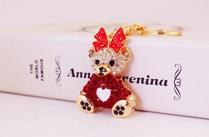 Detailed macro view of rhinestone teddy bear keychain with red bow on a book