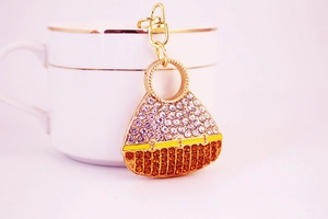 Macro detail of a crystal-encrusted handbag keychain with gold metal clasp and rhinestones