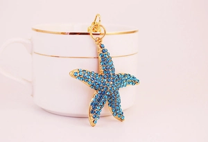 Détail d'un pendentif étoile de mer dorée avec cristaux bleus sur une tasse en céramique