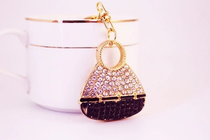 Close-up of golden handbag keychain with sparkling rhinestones and black enamel detail