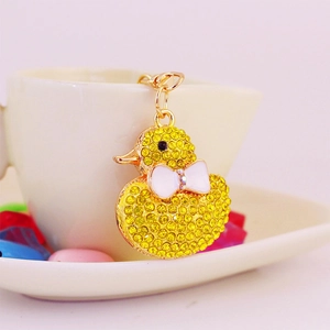 Funkelnder gelber Strass-Enten Schlüsselanhänger mit weißer Schleife an Kaffeetasse