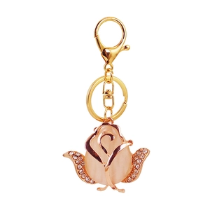 Golden rose keychain with opal center and white rhinestones on a white background