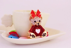 Detailed macro of a gold-plated bear keychain with sparkling red and white rhinestones