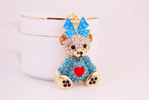 Close-up of a sparkling rhinestone teddy bear keychain with a blue bow and red heart