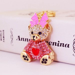 Sparkling rhinestone bear keychain with pink bow and red heart on book background