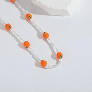 Handgemaakte kralenketting met witte heldere kralen en oranje dadelpruim hangers