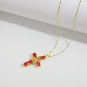 Close-up of golden cross necklace with red teardrop stones and Virgin Mary relief