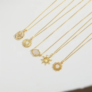 Cinq colliers dorés avec pendentifs soleil et flocon en zircon sur fond blanc pur