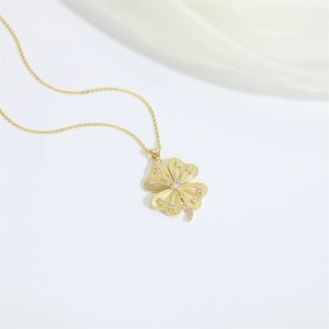 Detail of 14K gold clover pendant necklace featuring micro-set zircons and sunburst texture