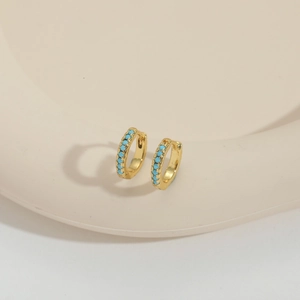 Bohemian gold hoop earrings with turquoise stones on minimalist ceramic display