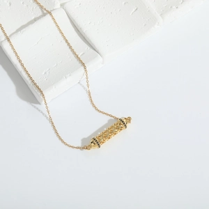 Detailed view of a gold hollow tube pendant with black zircon accents and a fine chain
