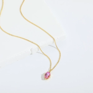Gros plan d'un pendentif en zircone rose sur une chaîne de collier dorée