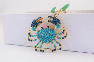 Gros plan d'un pendentif crabe doré avec strass bleus sur le bord d'une boîte