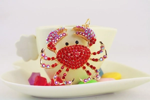 Vue détaillée d'un pendentif crabe avec strass rouges accroché à une tasse de café