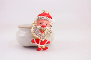 Close-up of Santa Claus charm with red enamel, gold metal frame and sparkling rhinestones