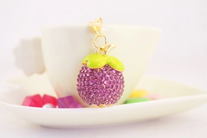 Détail d'un porte-clés mangoustan avec strass violets et feuille en émail vert
