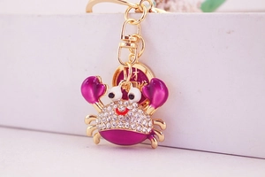 Macro view of purple crab keychain with white rhinestones and a golden fortune coin charm